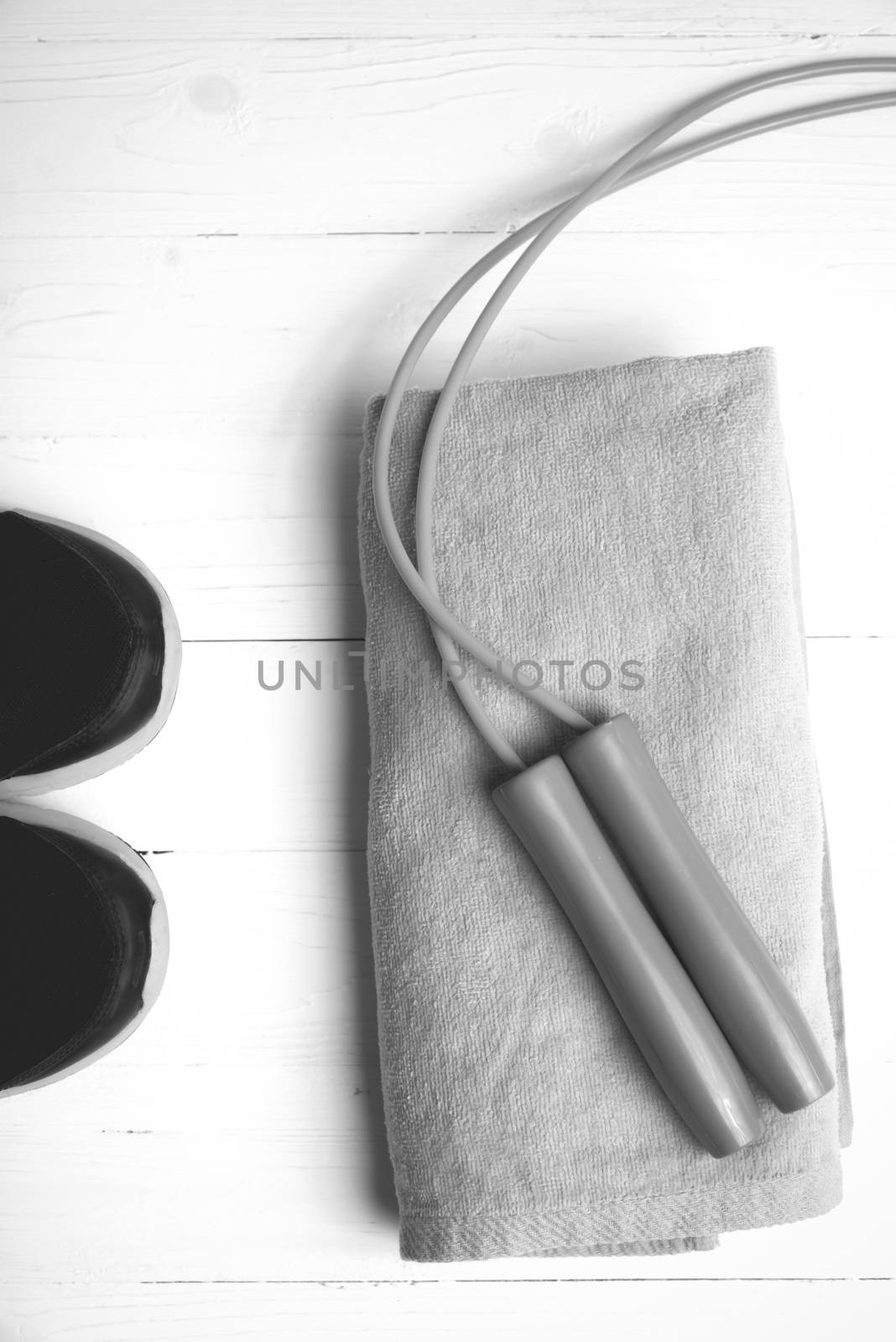 fitness equipment: towel,jumping rope and running shoes on white wood table black and white color style