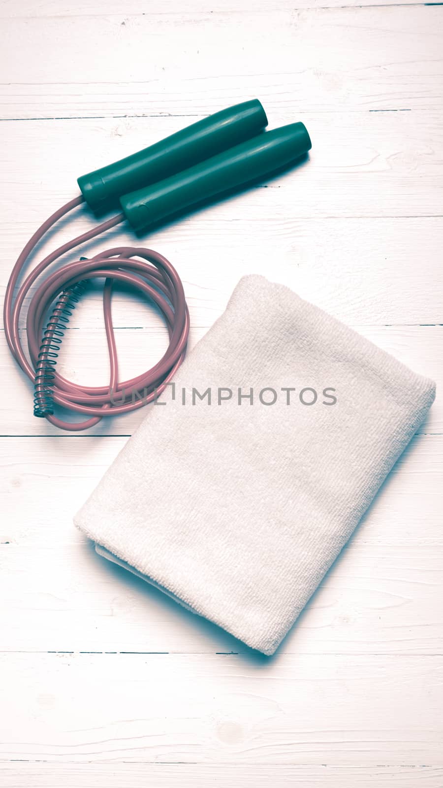 fitness equipment:white towel,jumping rope on white wood table vintage style