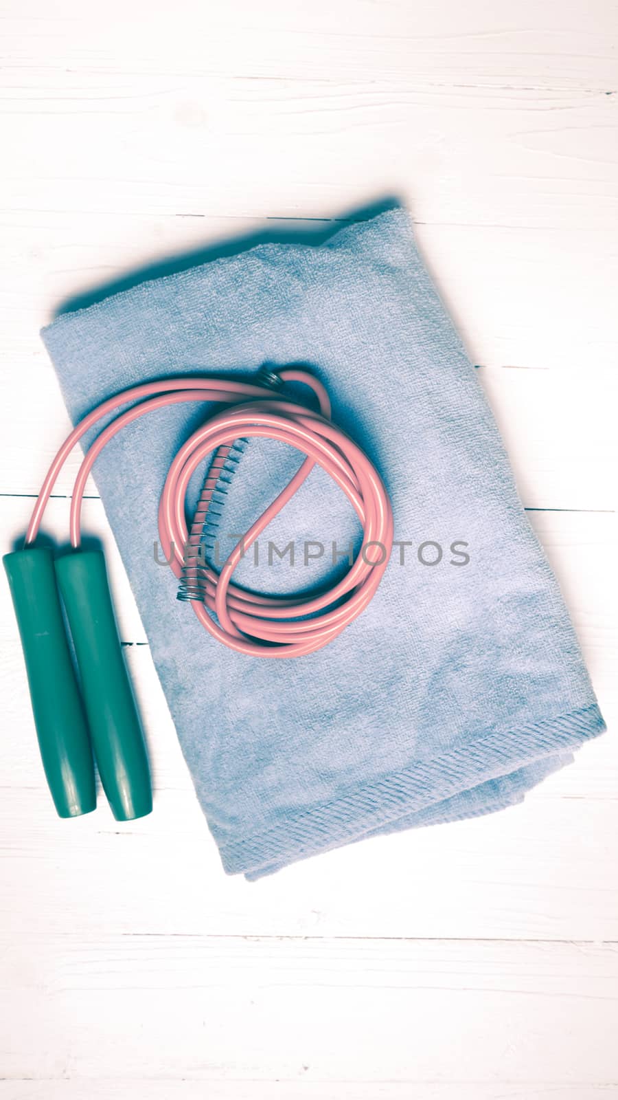 fitness equipment:blue towel,jumping rope on white wood table vintage style