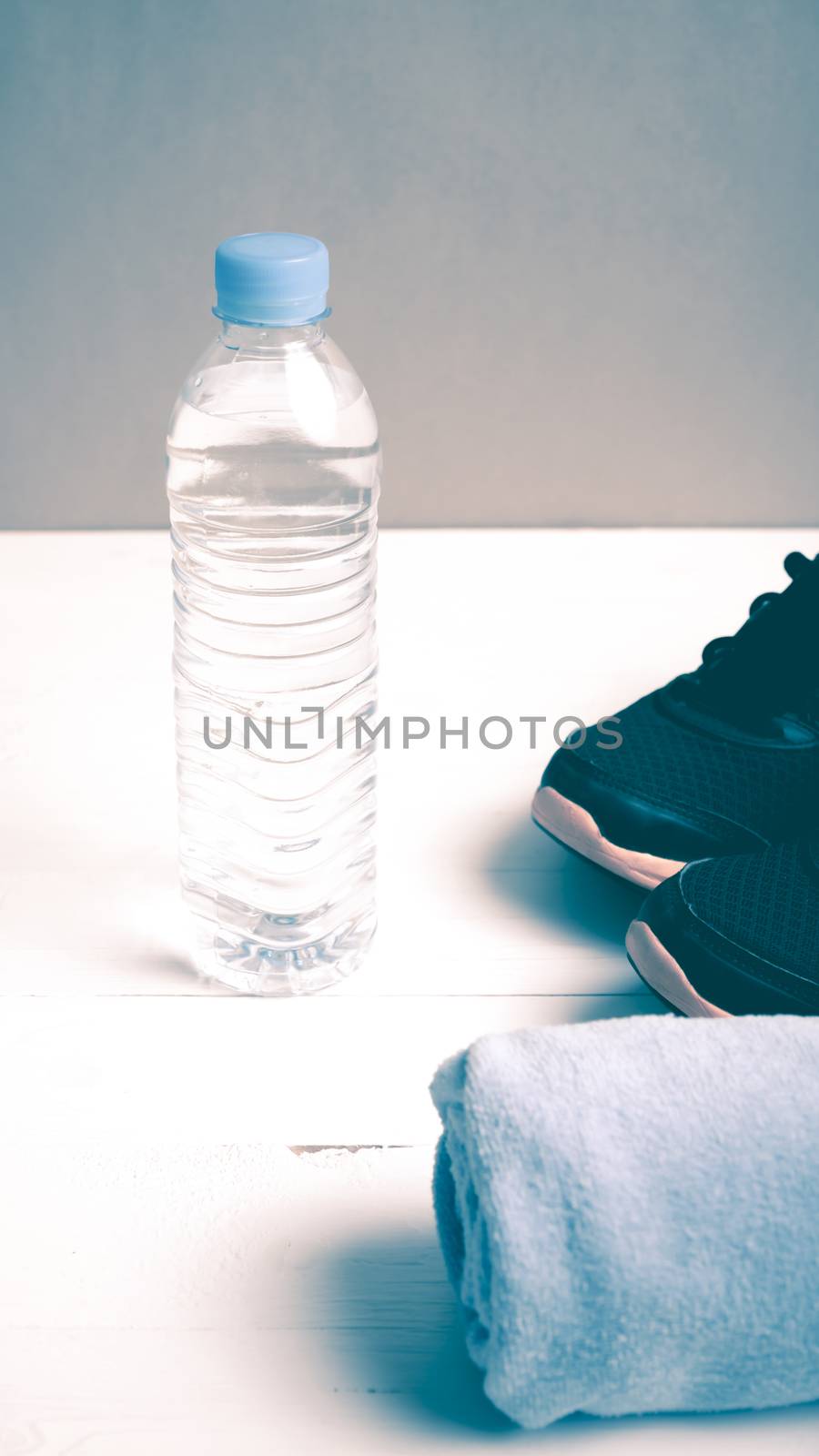 fitness equipment:blue towel,drinking water and running shoes on white wood table vintage style