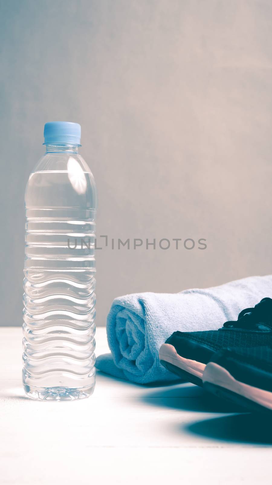 fitness equipment:blue towel,drinking water and running shoes on white wood table vintage style