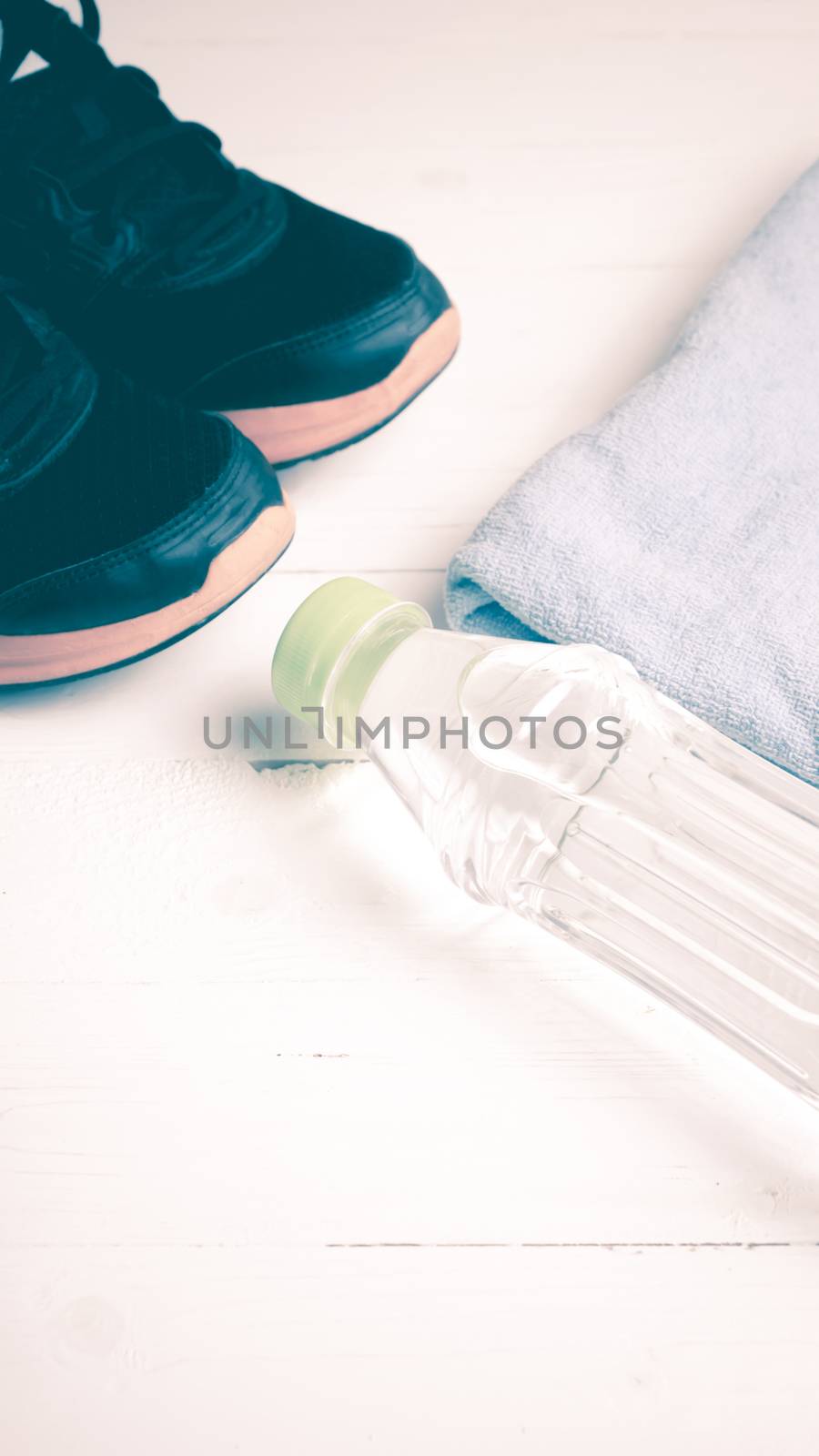 fitness equipment:blue towel,drinking water and running shoes on white wood table vintage style