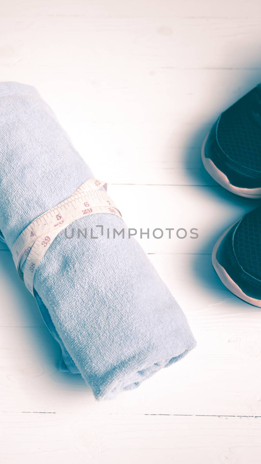 fitness equipment : running shoes,blue towel and measuring tape on white wood table vintage style