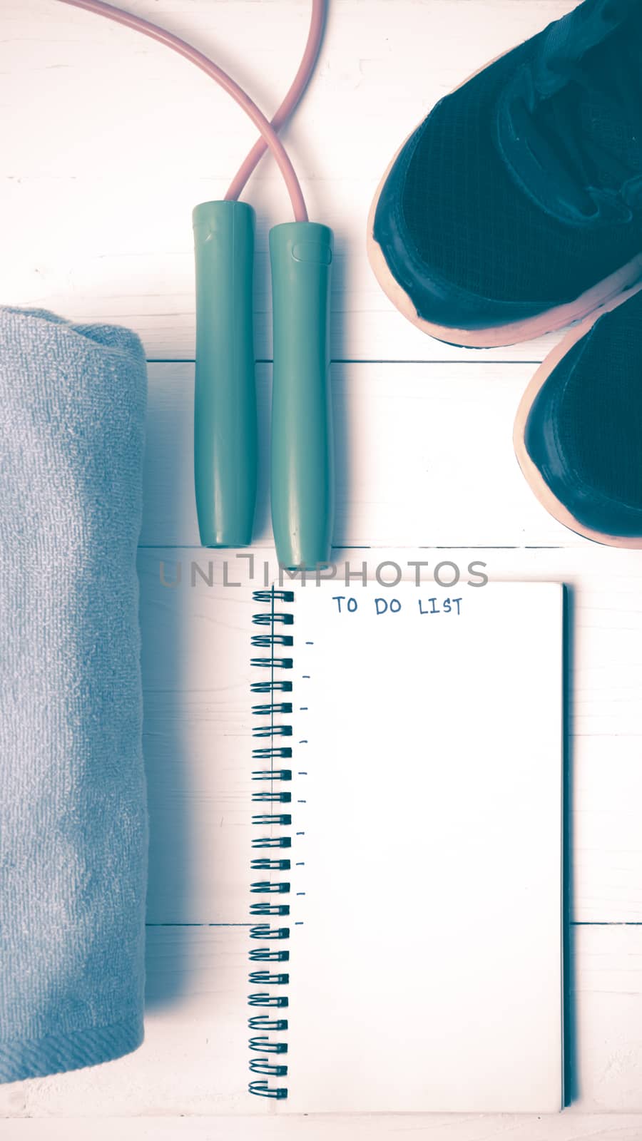 fitness equipment : running shoes,towel,jumping rope and notebook write to do list on white wood table vintage style