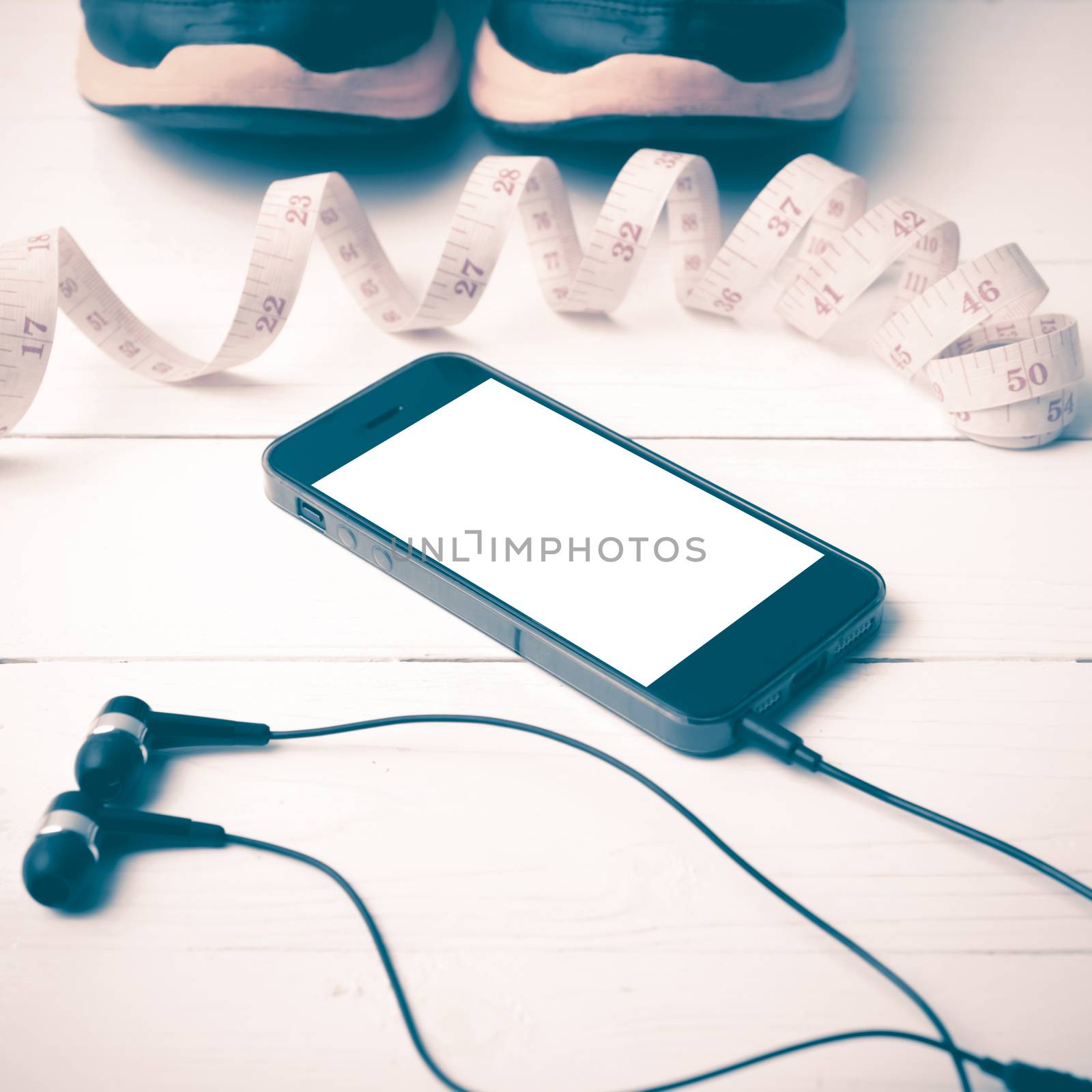 running shoes,measuring tape and phone on white wood table vintage style