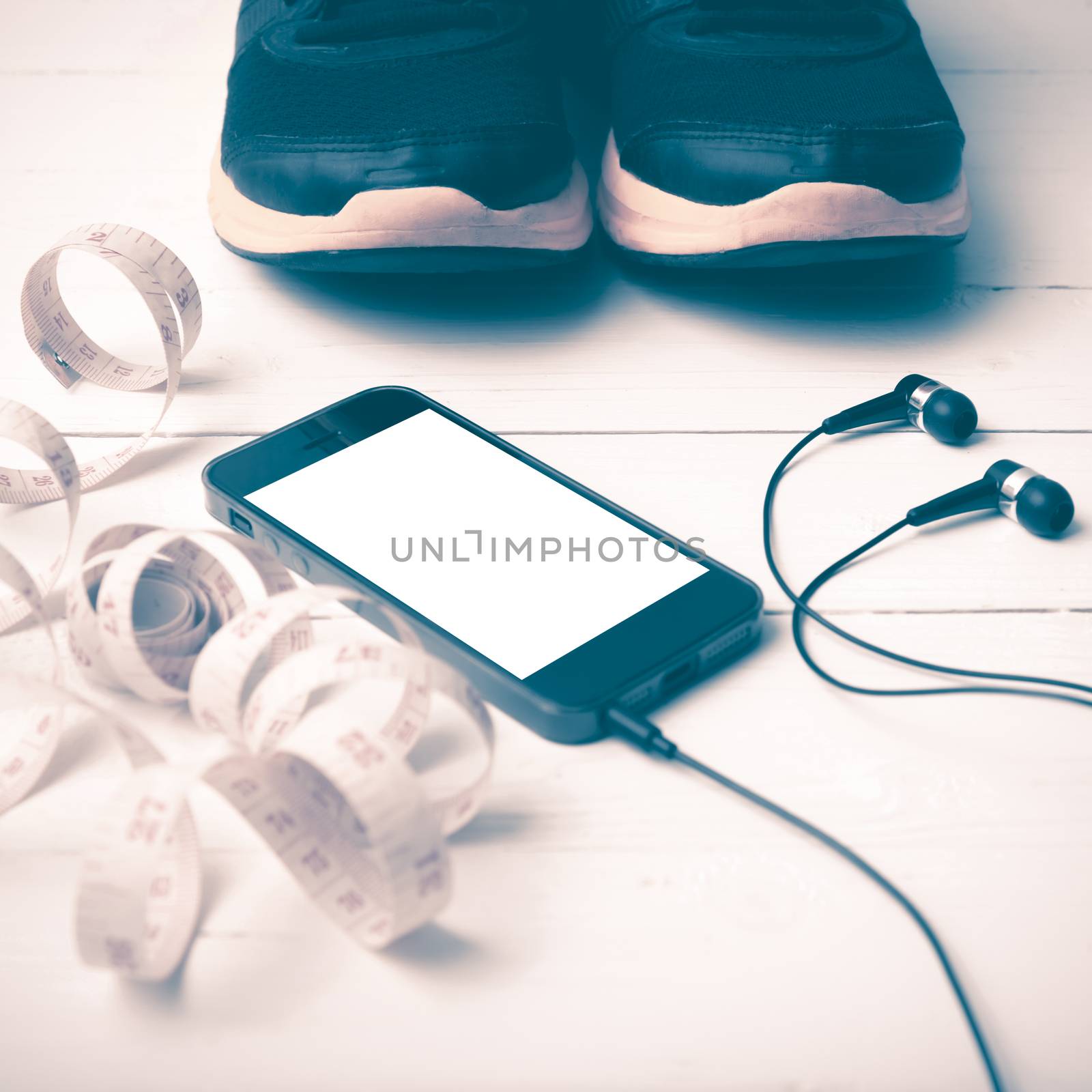 running shoes,measuring tape and phone on white wood table vintage style