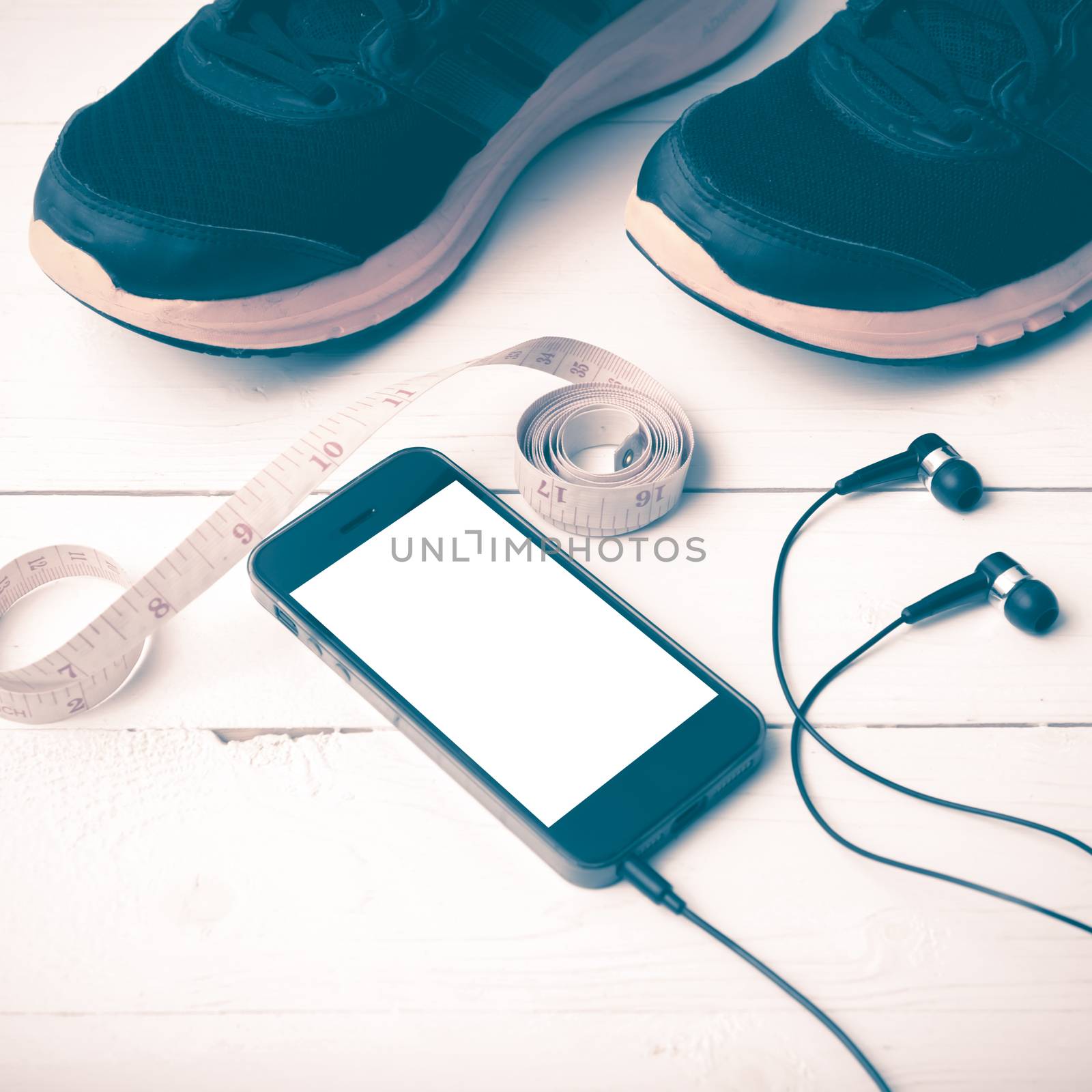 running shoes,measuring tape and phone on white wood table vintage style