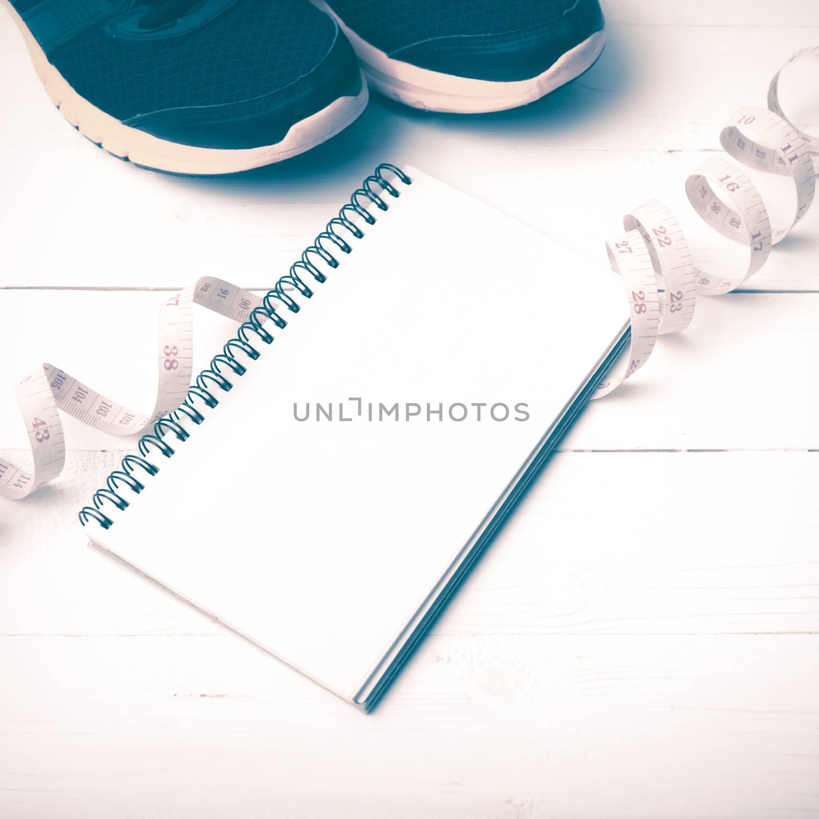 running shoes with notebook and measuring tape on white wood table vintage style