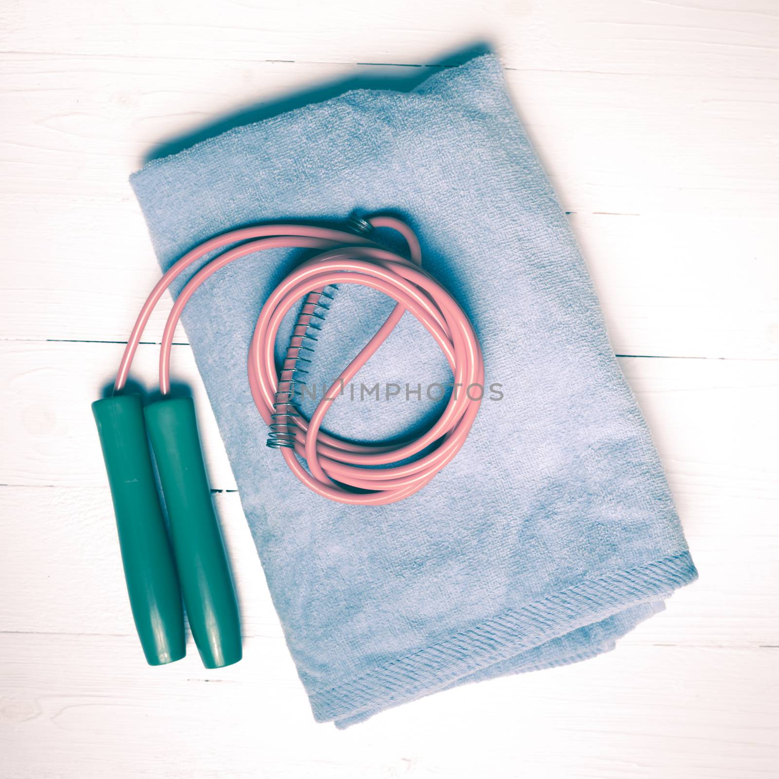 fitness equipment:blue towel,jumping rope on white wood table vintage style