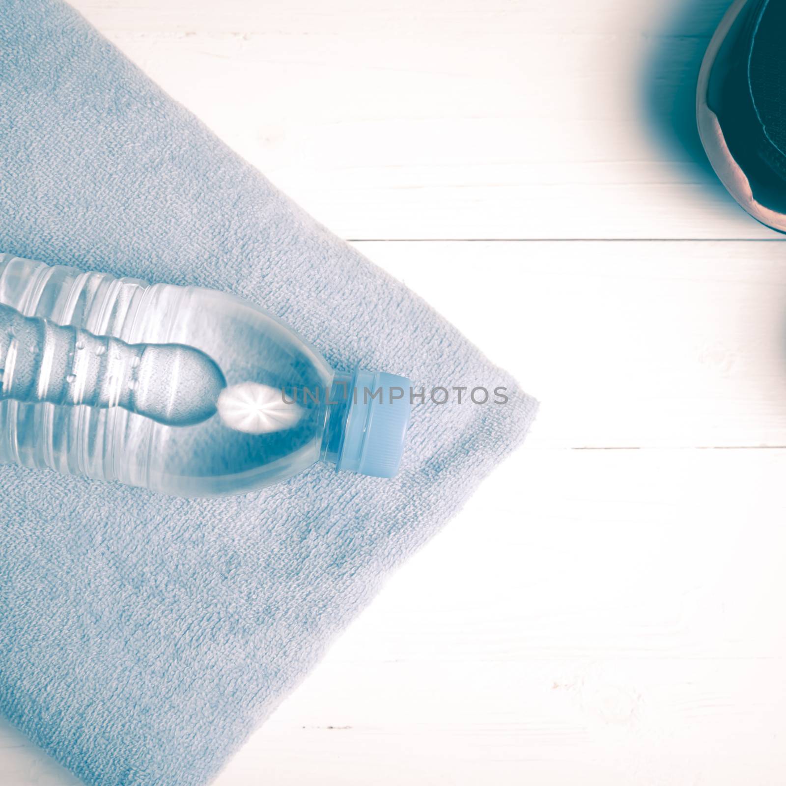 fitness equipment:blue towel,drinking water and running shoes on white wood table vintage style