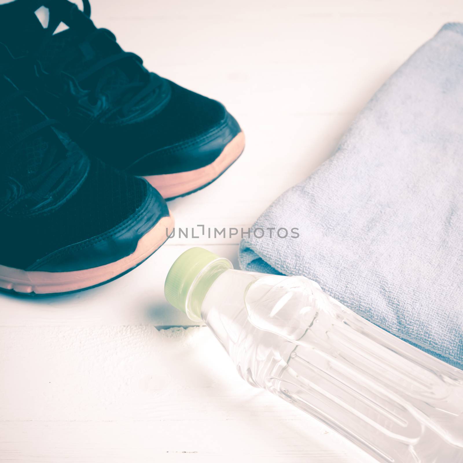 fitness equipment:blue towel,drinking water and running shoes on white wood table vintage style