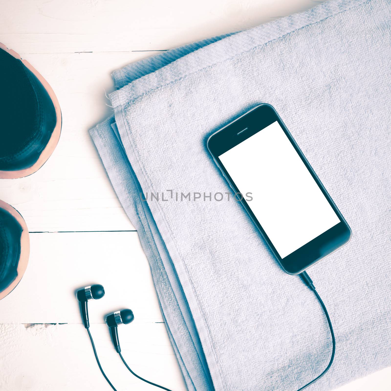 fitness equipment:running shoes,blue towel and smart phone on white wood table vintage style