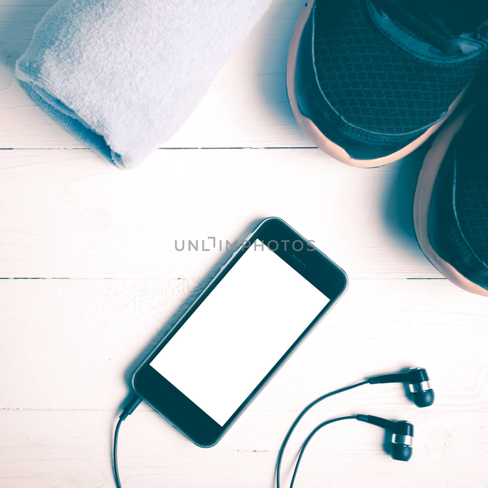 fitness equipment:running shoes,blue towel and smart phone on white wood table vintage style