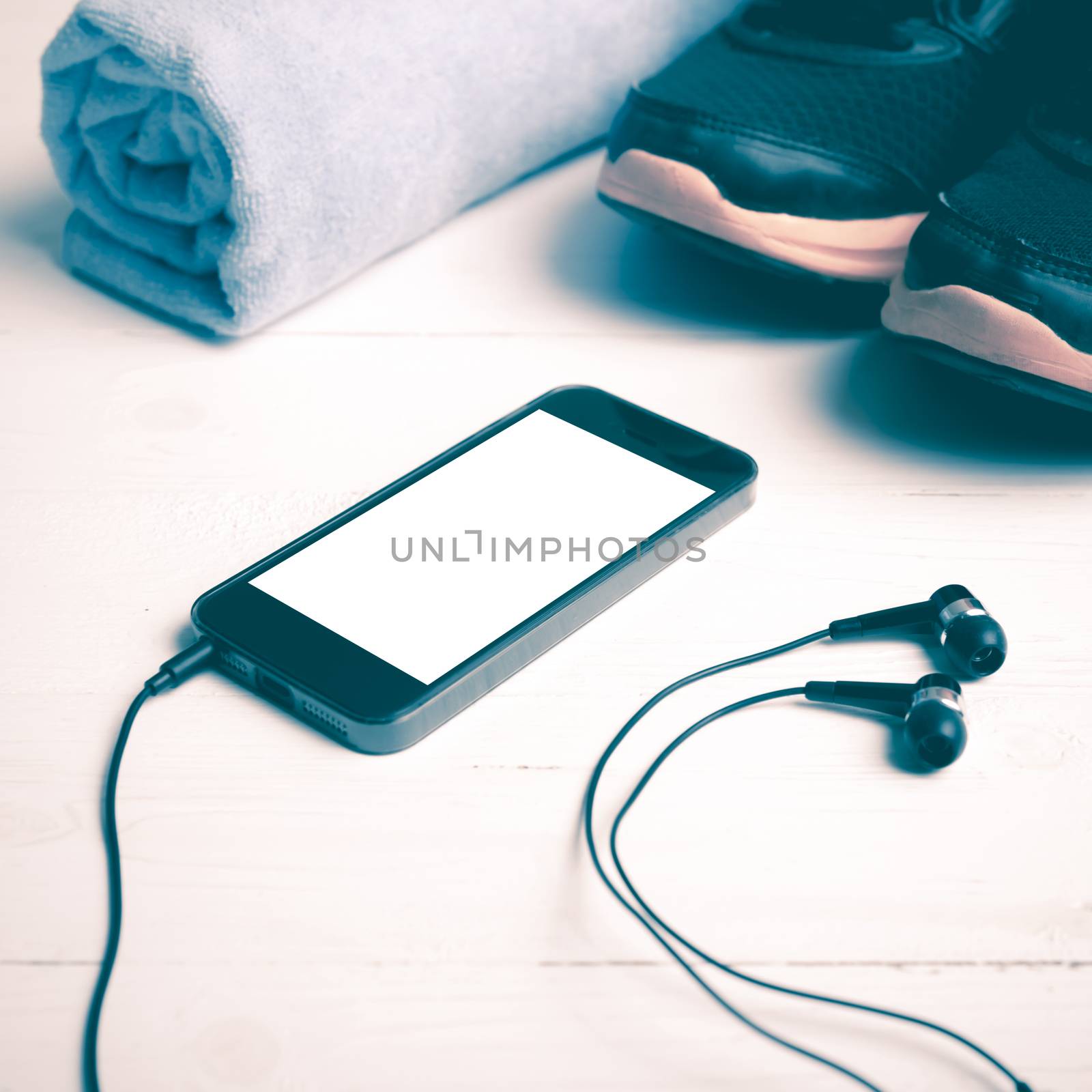 fitness equipment:running shoes,blue towel and smart phone on white wood table vintage style