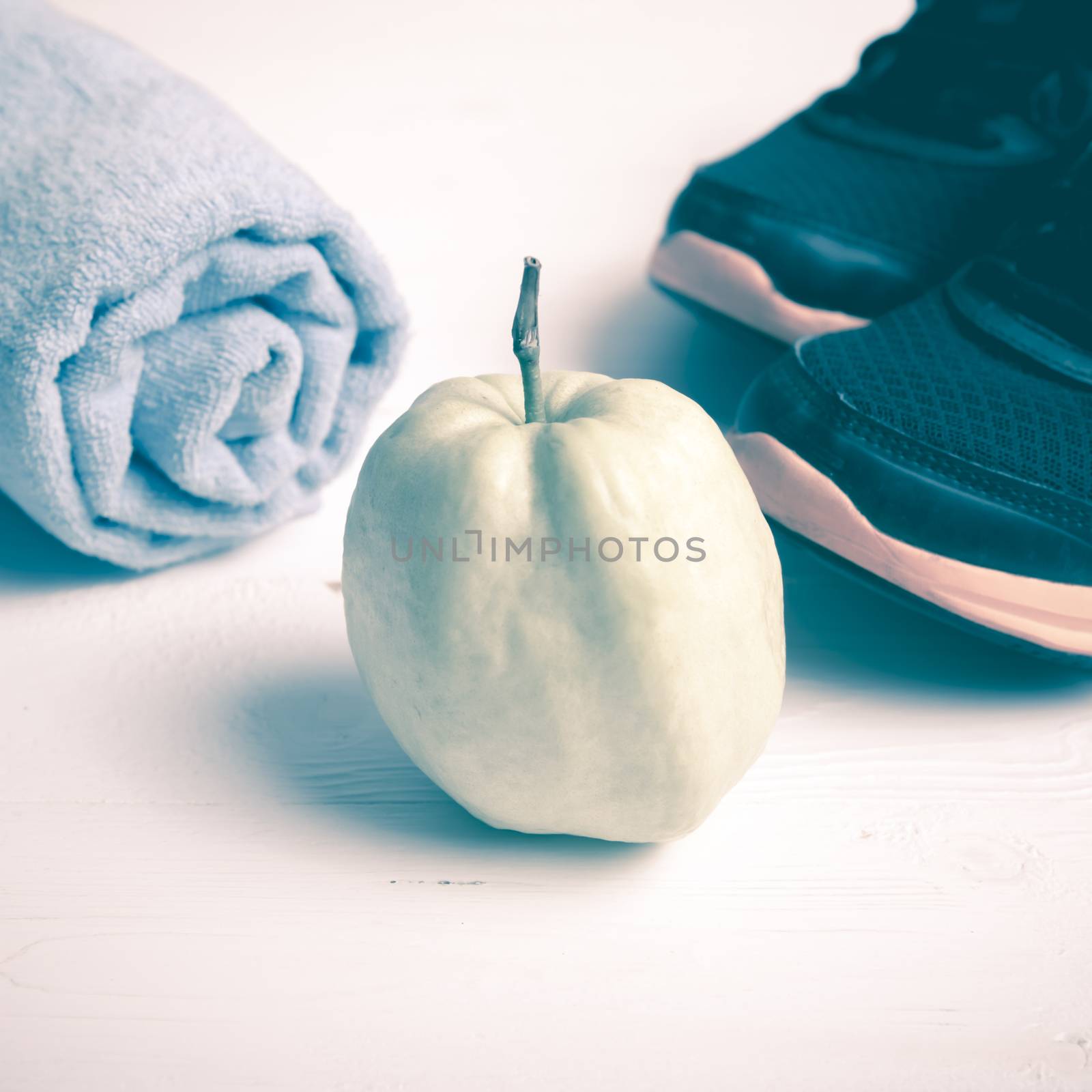 fitness equipment : running shoes,blue towel and guava fruit on white wood table vintage style