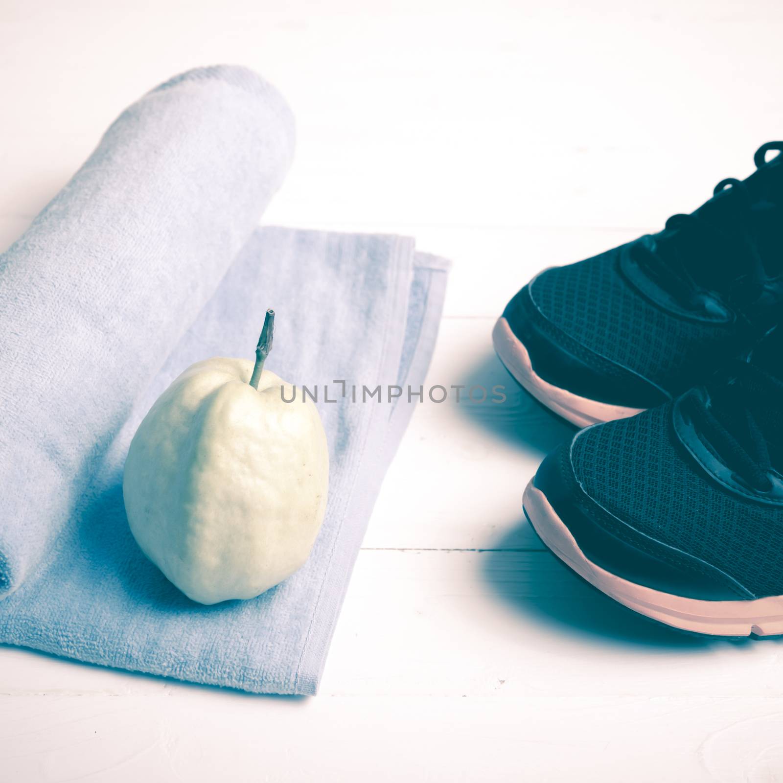 fitness equipment : running shoes,blue towel and guava fruit on white wood table vintage style