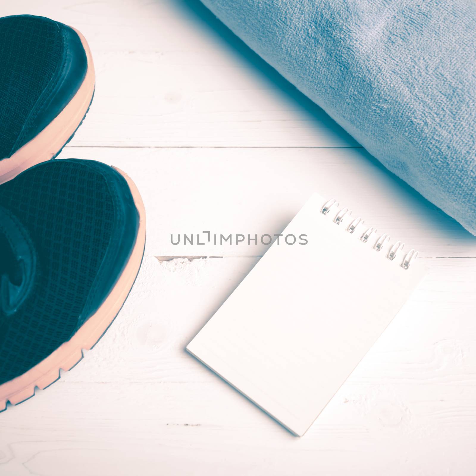 fitness equipment : running shoes,blue towel and notepad on white wood table vintage style