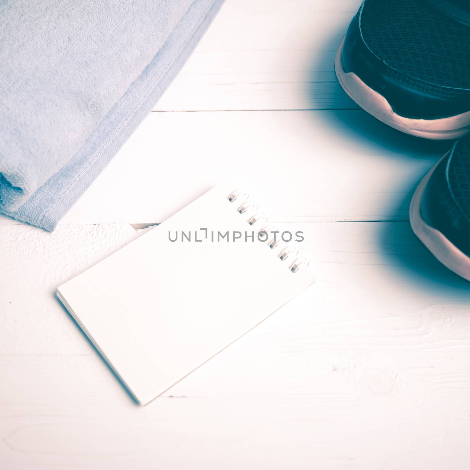 fitness equipment : running shoes,blue towel and notepad on white wood table vintage style