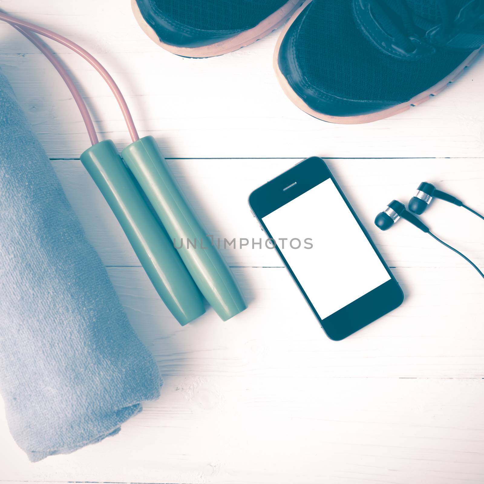 fitness equipment : running shoes,towel,jumping rope and phone on white wood table vintage style