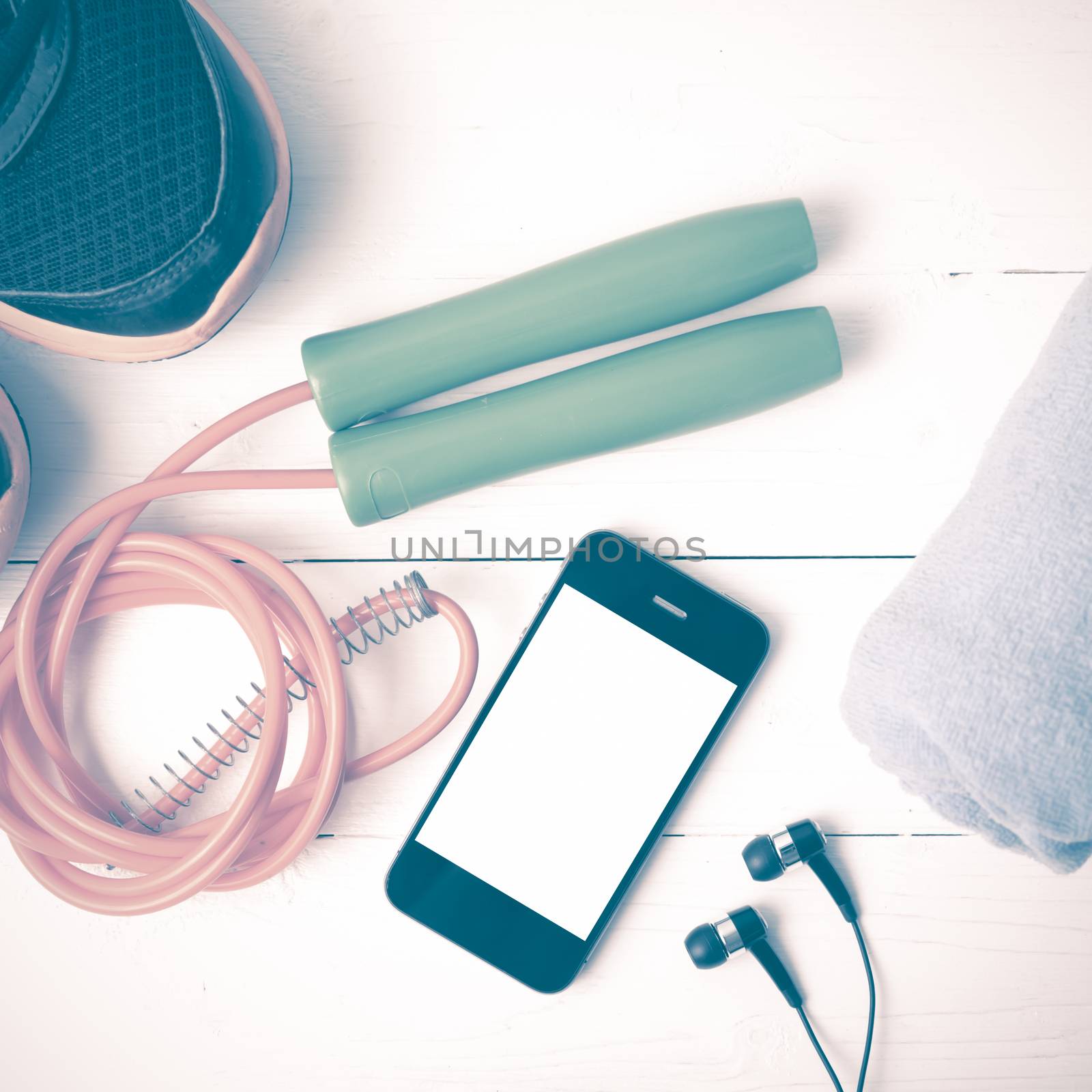 fitness equipment : running shoes,towel,jumping rope and phone on white wood table vintage style