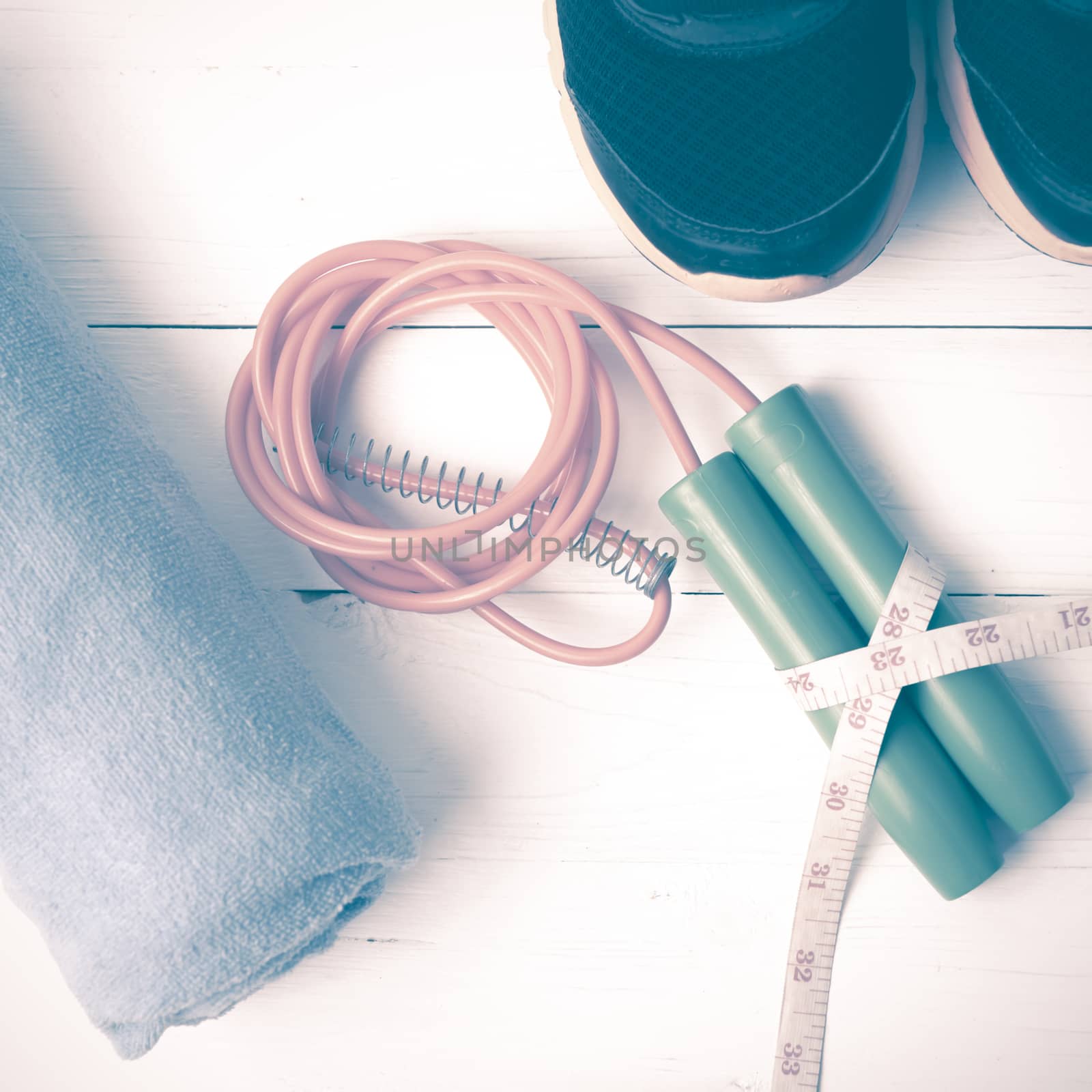 fitness equipment : running shoes,towel,jumping rope and measuring tape on white wood table vintage style