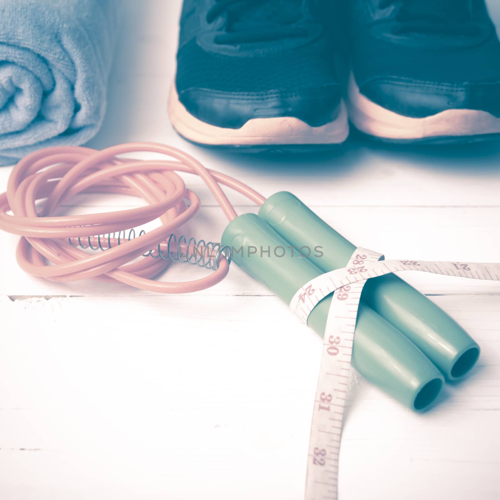 fitness equipment : running shoes,towel,jumping rope and measuring tape on white wood table vintage style