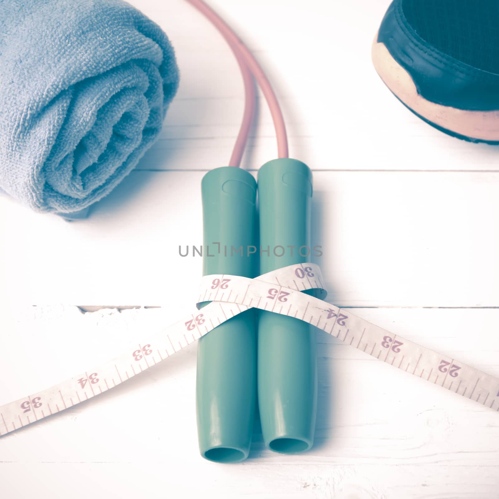 fitness equipment : running shoes,towel,jumping rope and measuring tape on white wood table vintage style
