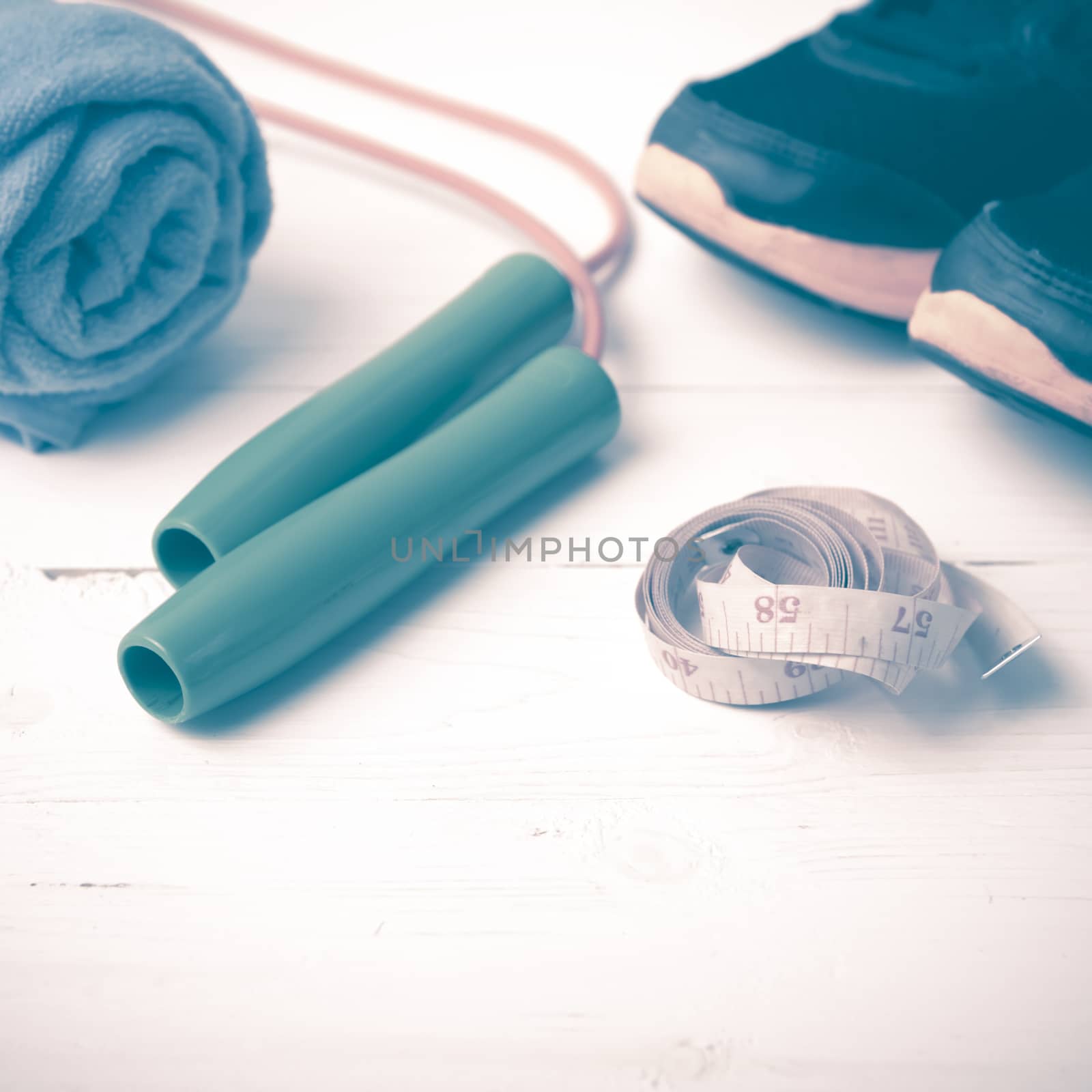 fitness equipment : running shoes,towel,jumping rope and measuring tape on white wood table vintage style