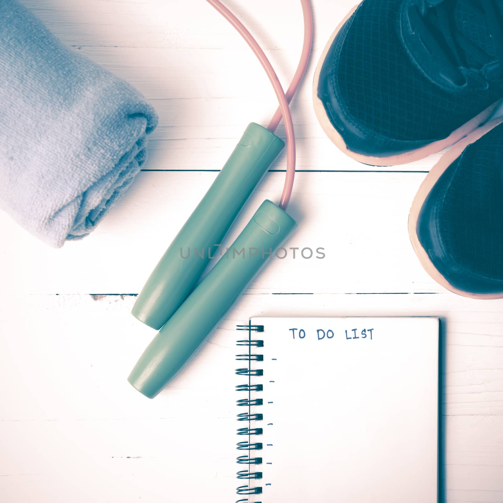 fitness equipment : running shoes,towel,jumping rope and notebook write to do list on white wood table vintage style