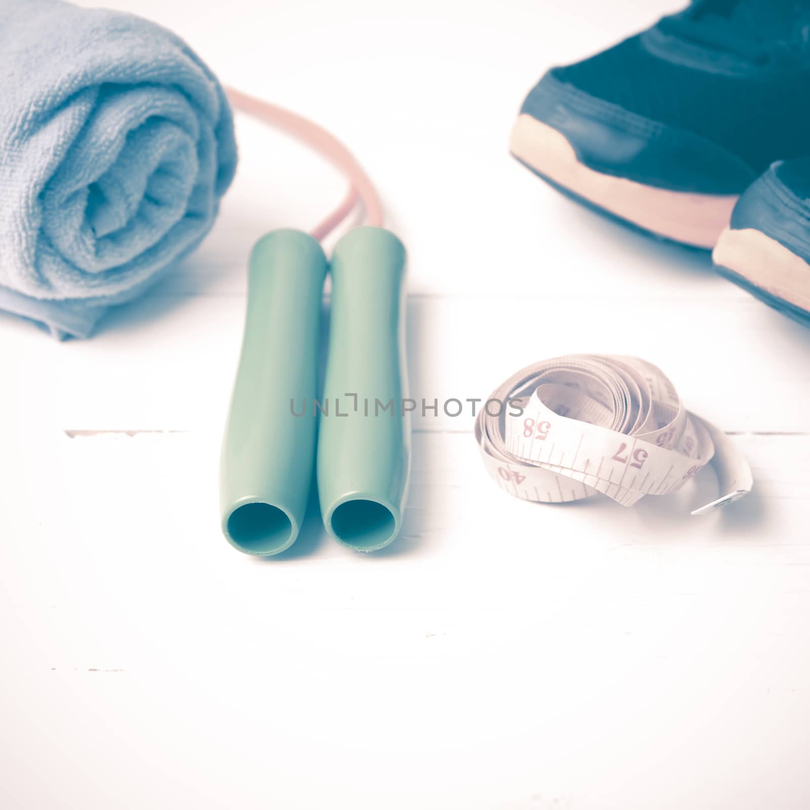fitness equipment : running shoes,towel,jumping rope and measuring tape on white wood table vintage style