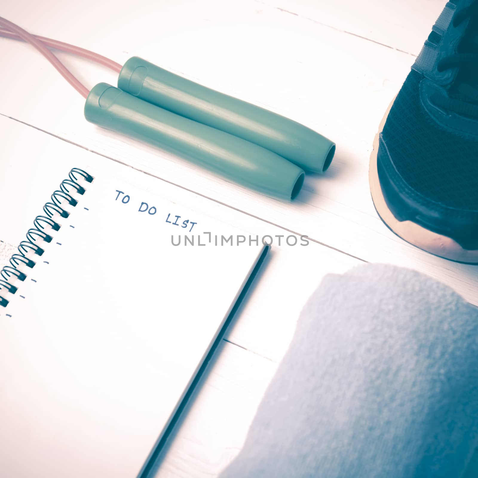 fitness equipment : running shoes,towel,jumping rope and notebook write to do list on white wood table vintage style