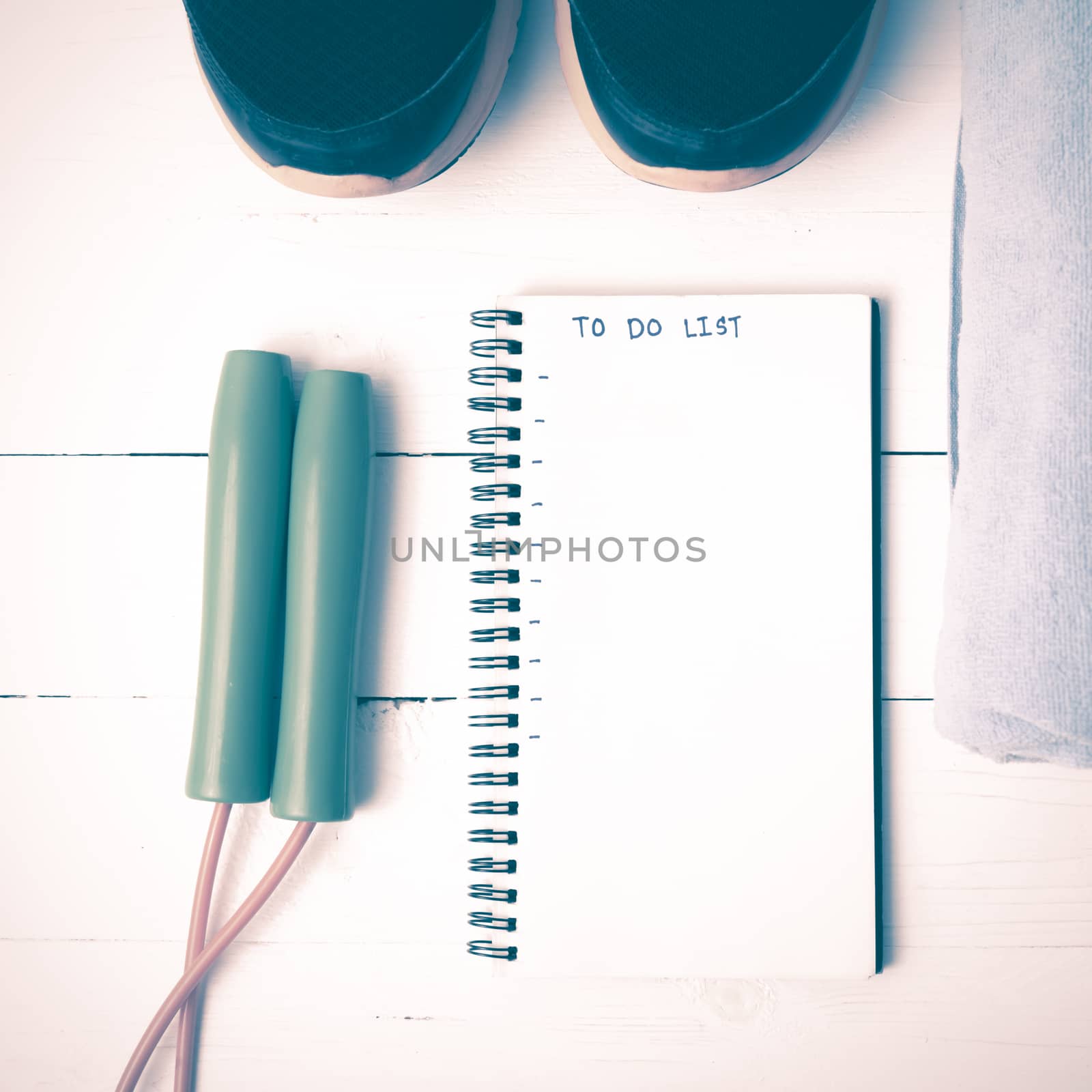 fitness equipment : running shoes,towel,jumping rope and notebook write to do list on white wood table vintage style