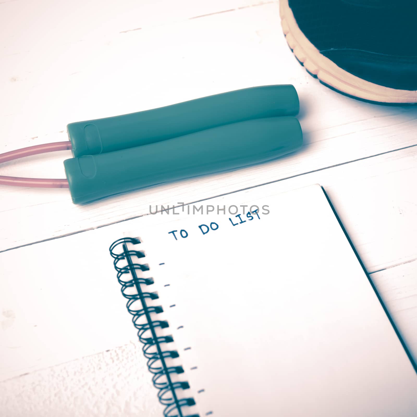 fitness equipment : running shoes,jumping rope and notebook write to do list on white wood table vintage style