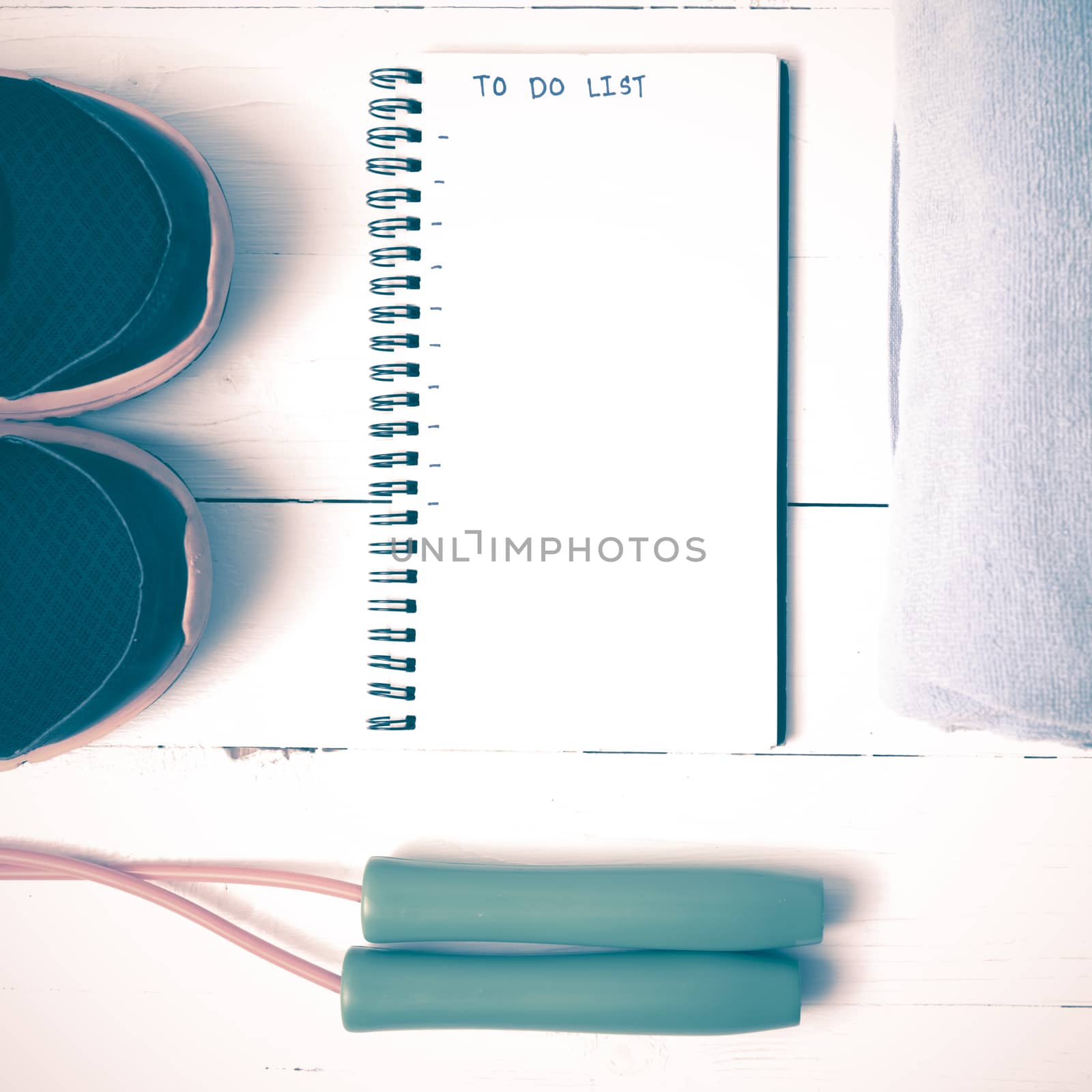 fitness equipment : running shoes,towel,jumping rope and notebook write to do list on white wood table vintage style