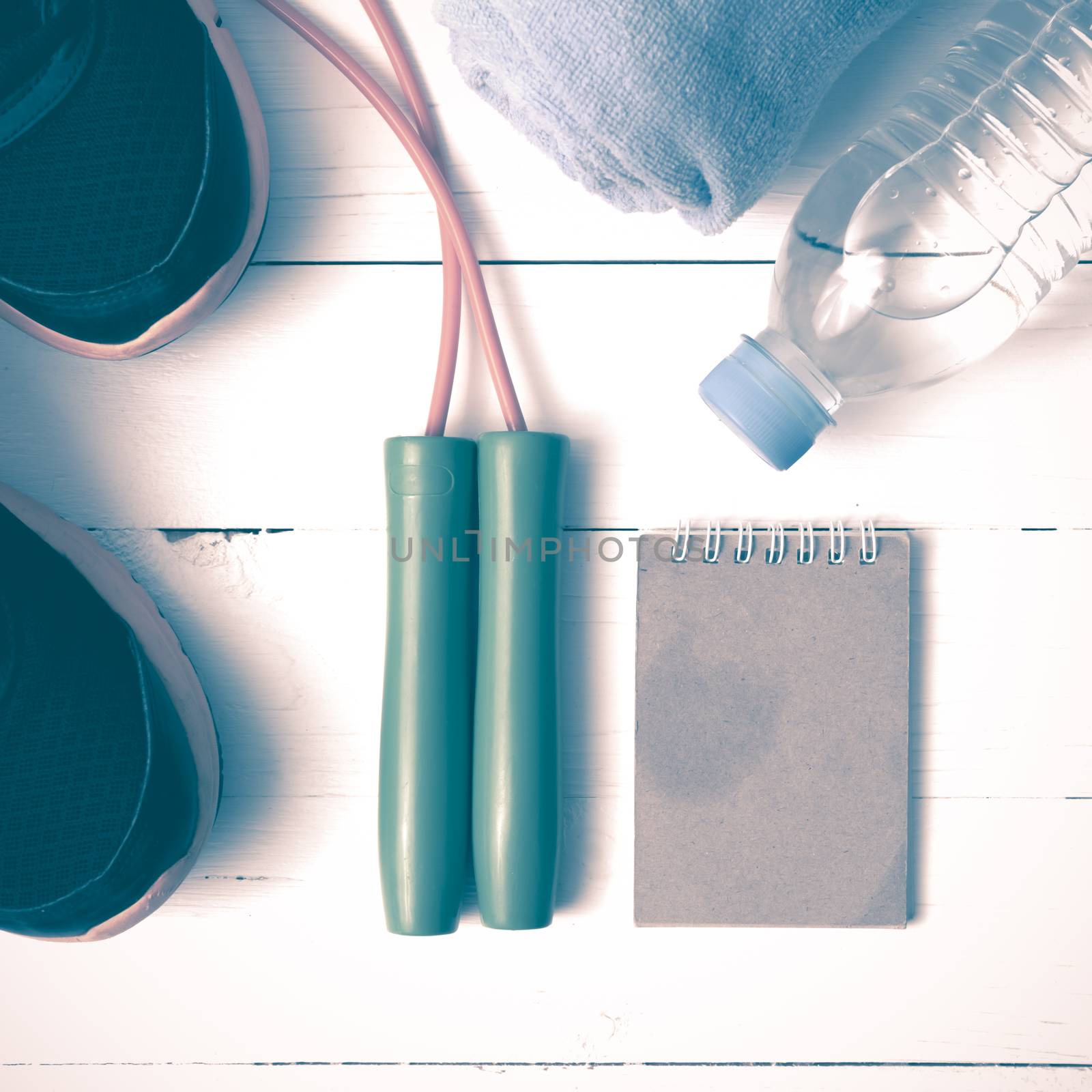 fitness equipment : running shoes,towel,jumping rope,water bottle and notepad on white wood table vintage style