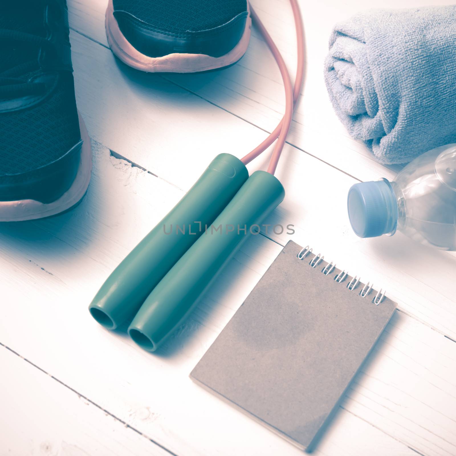 fitness equipment : running shoes,towel,jumping rope,water bottle and notepad on white wood table vintage style