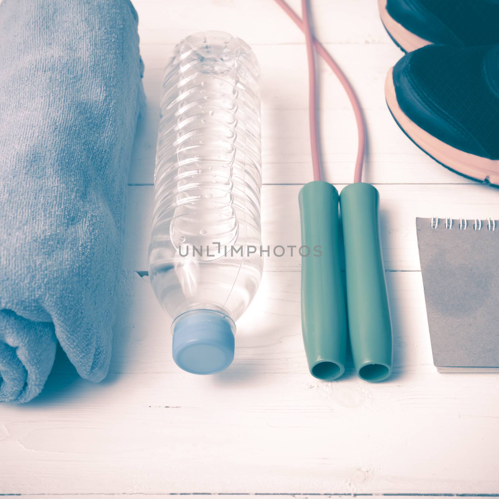 fitness equipment : running shoes,towel,jumping rope,water bottle and notepad on white wood table vintage style