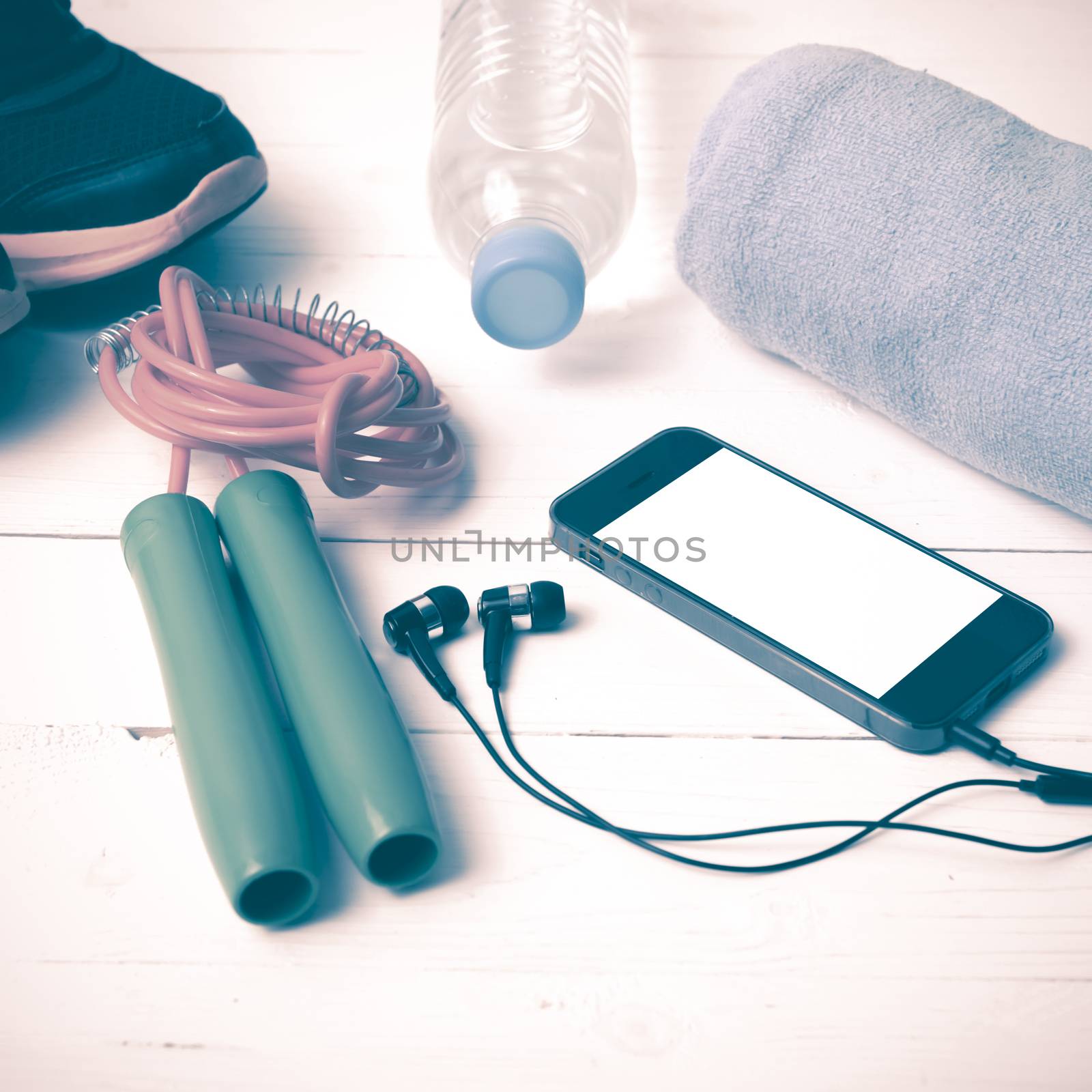 fitness equipment : running shoes,towel,jumping rope,water bottle and phone on white wood table vintage style