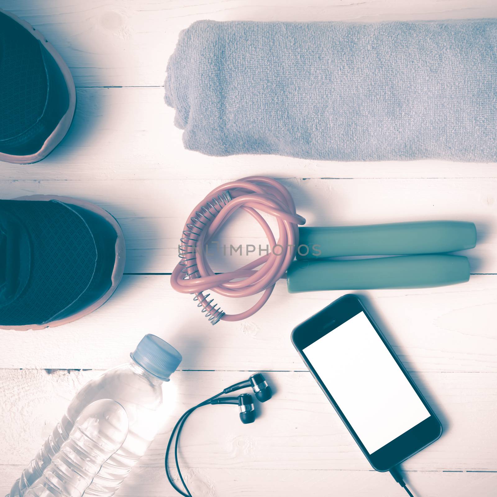 fitness equipment : running shoes,towel,jumping rope,water bottle and phone on white wood table vintage style