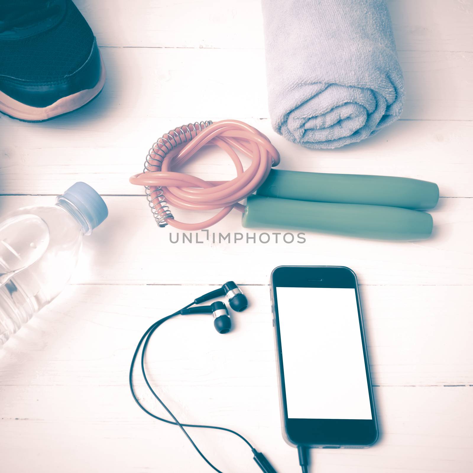 fitness equipment : running shoes,towel,jumping rope,water bottle and phone on white wood table vintage style