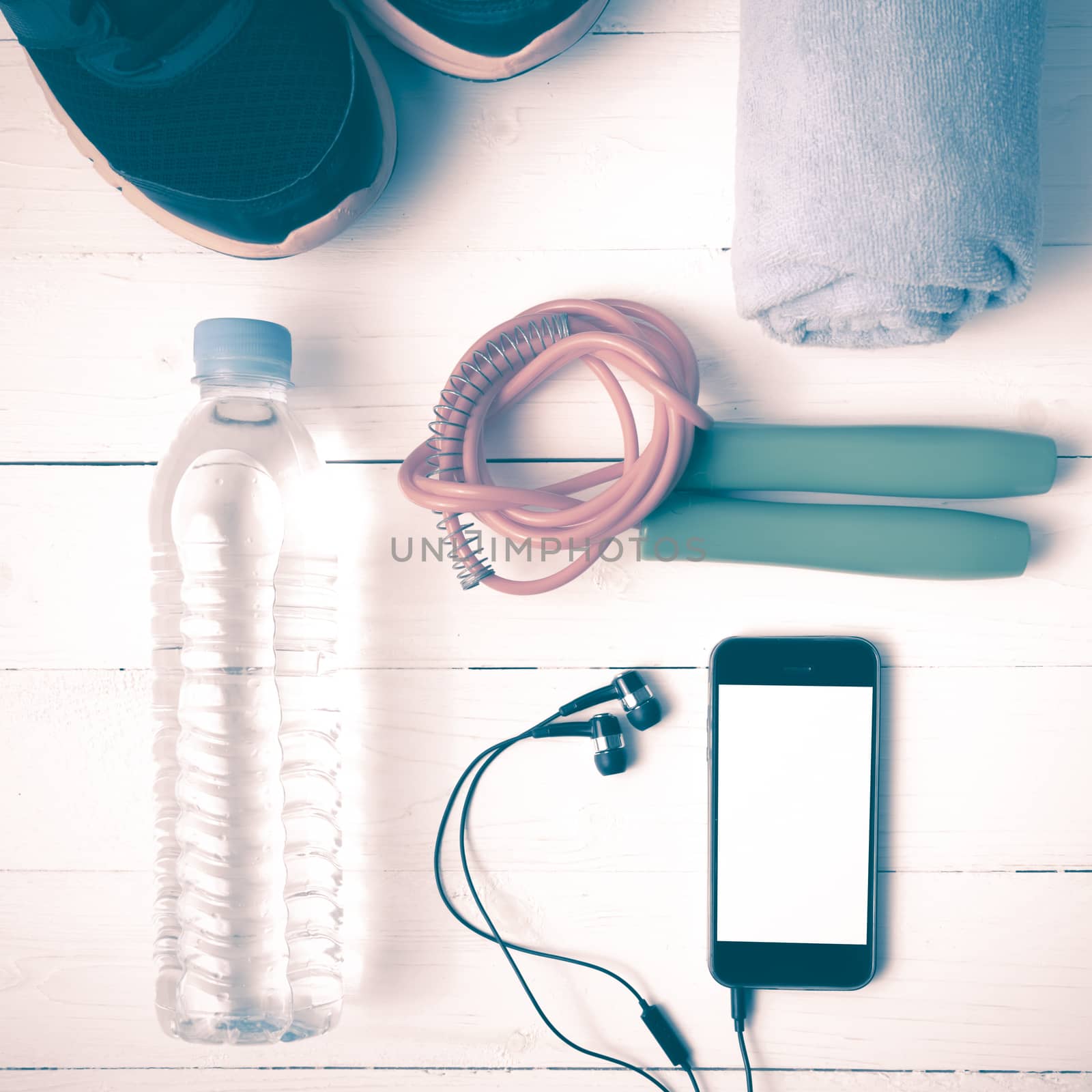 fitness equipment : running shoes,towel,jumping rope,water bottle and phone on white wood table vintage style