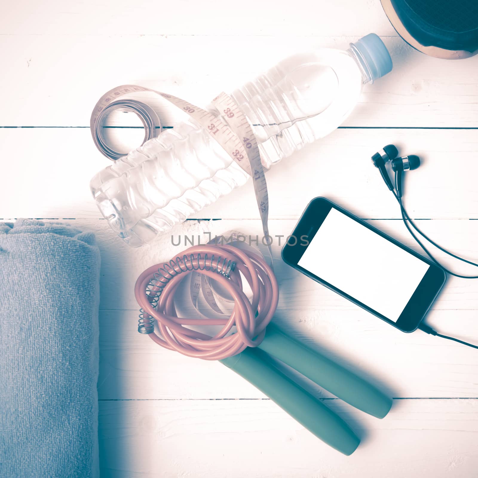 fitness equipment : running shoes,towel,jumping rope,water bottle,phone and measuring tape on white wood table vintage style