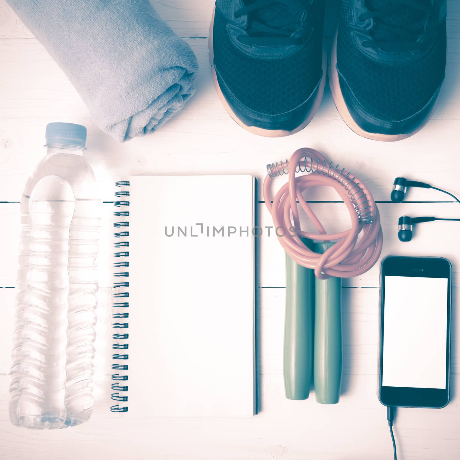 fitness equipment : running shoes,towel,jumping rope,water bottle,phone and notepad on white wood table vintage style