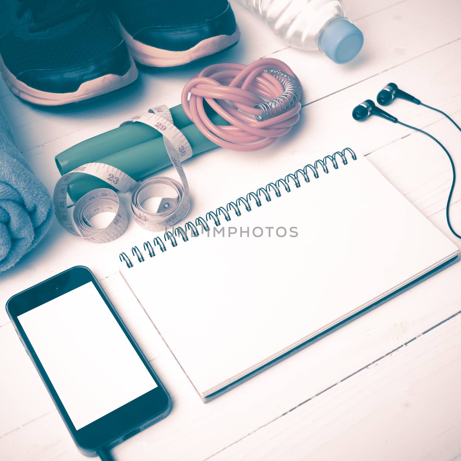 fitness equipment : running shoes,towel,jumping rope,water bottle,phone,notepad and measuring tape on white wood table vintage style