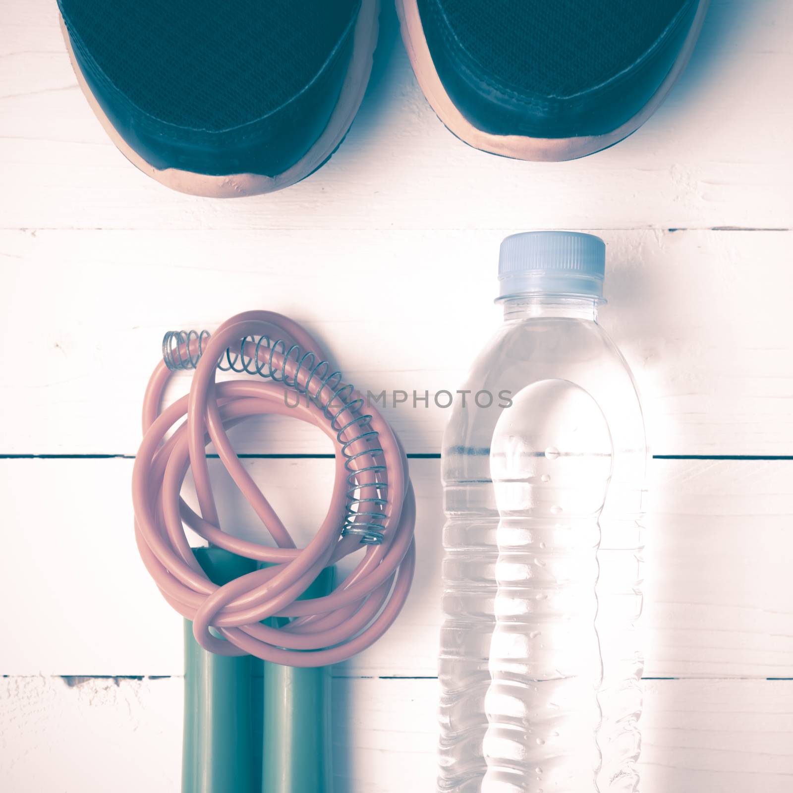fitness equipment : running shoes,jumping rope and water bottle on white wood table vintage style
