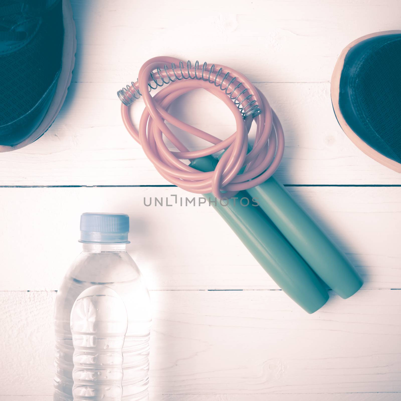 fitness equipment : running shoes,jumping rope and water bottle on white wood table vintage style