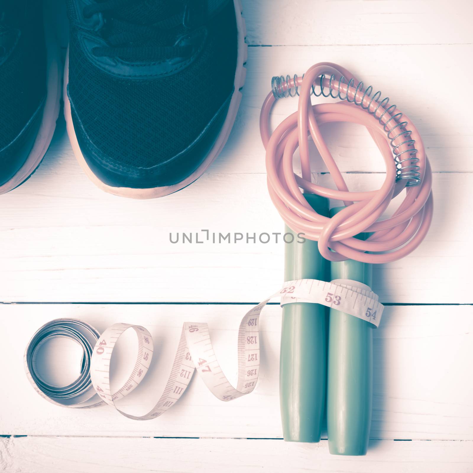 fitness equipment : running shoes,jumping rope and measuring tape on white wood table vintage style