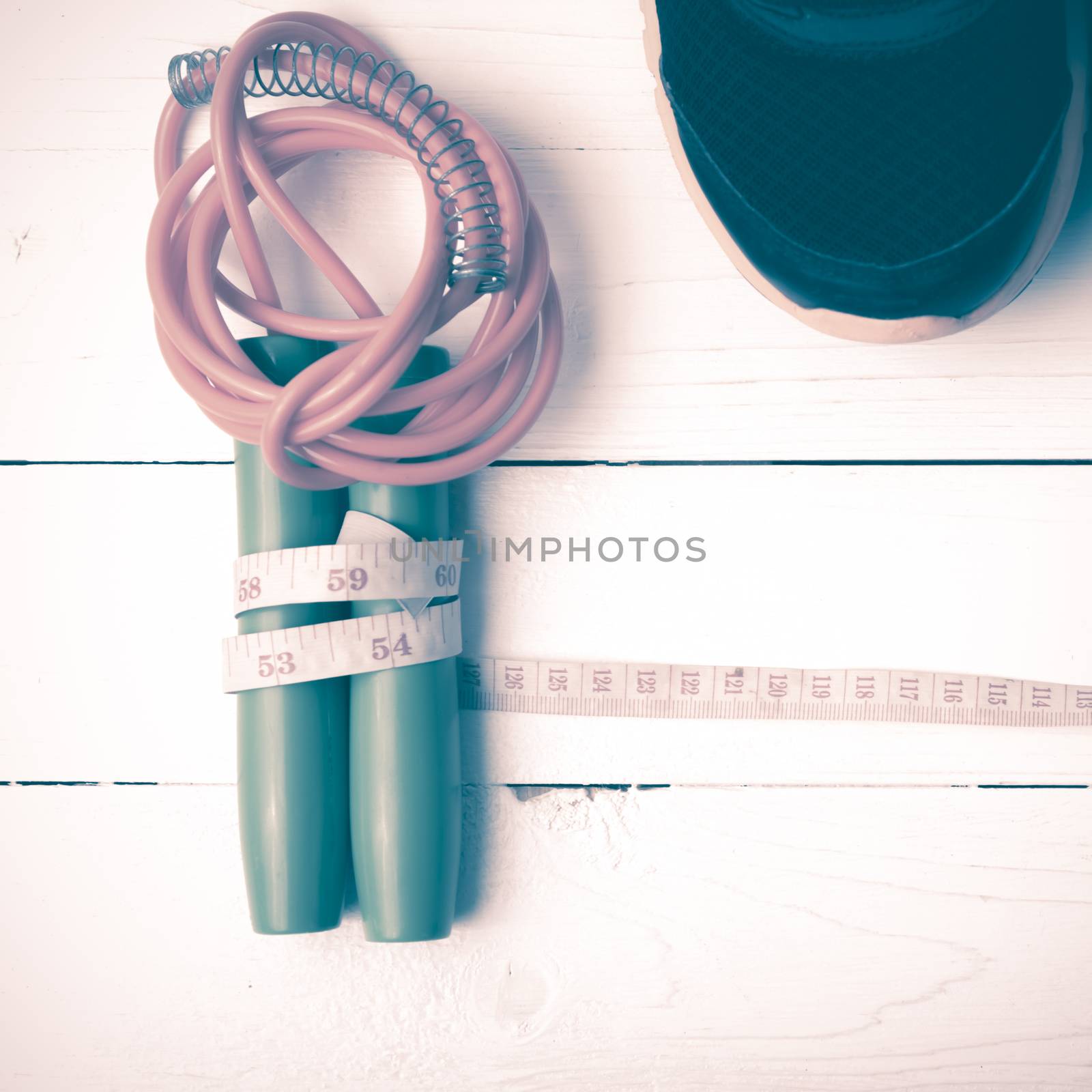 fitness equipment : running shoes,jumping rope and measuring tape on white wood table vintage style