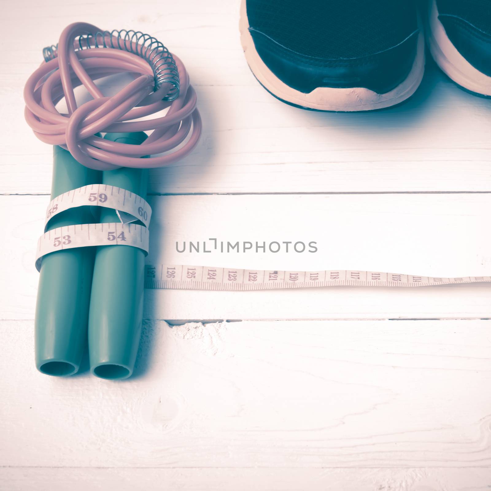 fitness equipment : running shoes,jumping rope and measuring tape on white wood table vintage style