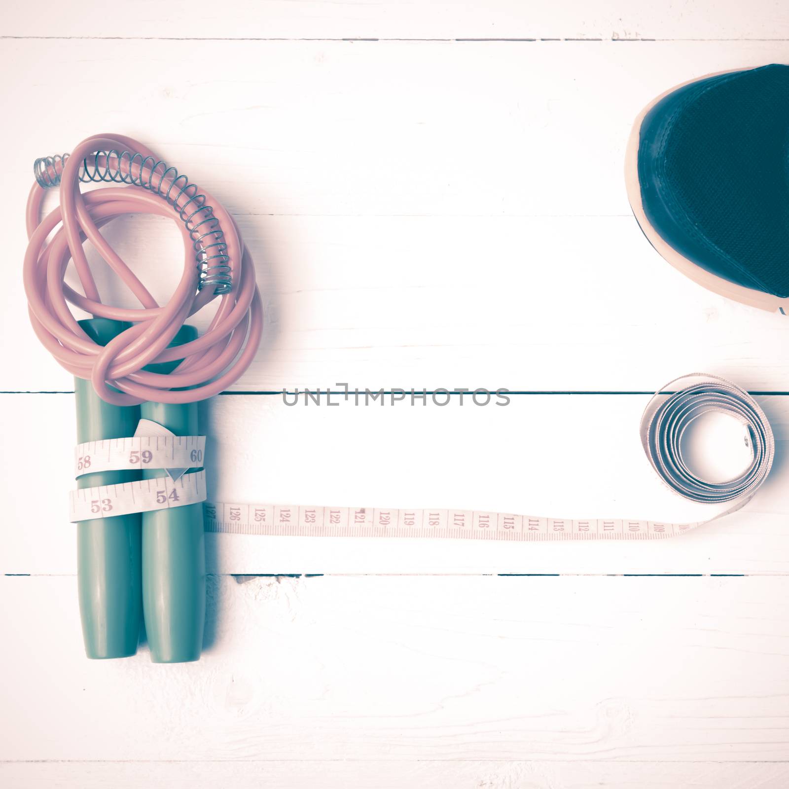 fitness equipment : running shoes,jumping rope and measuring tape on white wood table vintage style